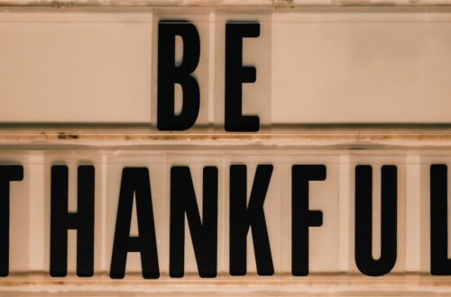 Black letters spell out "be thankful" on a sign.